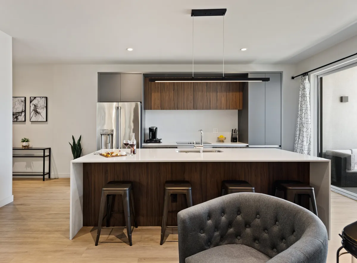A welcoming kitchen with a central island, comfortable stools, modern appliances, and decorative wall art—ideal for group gatherings and easy meal preparation.