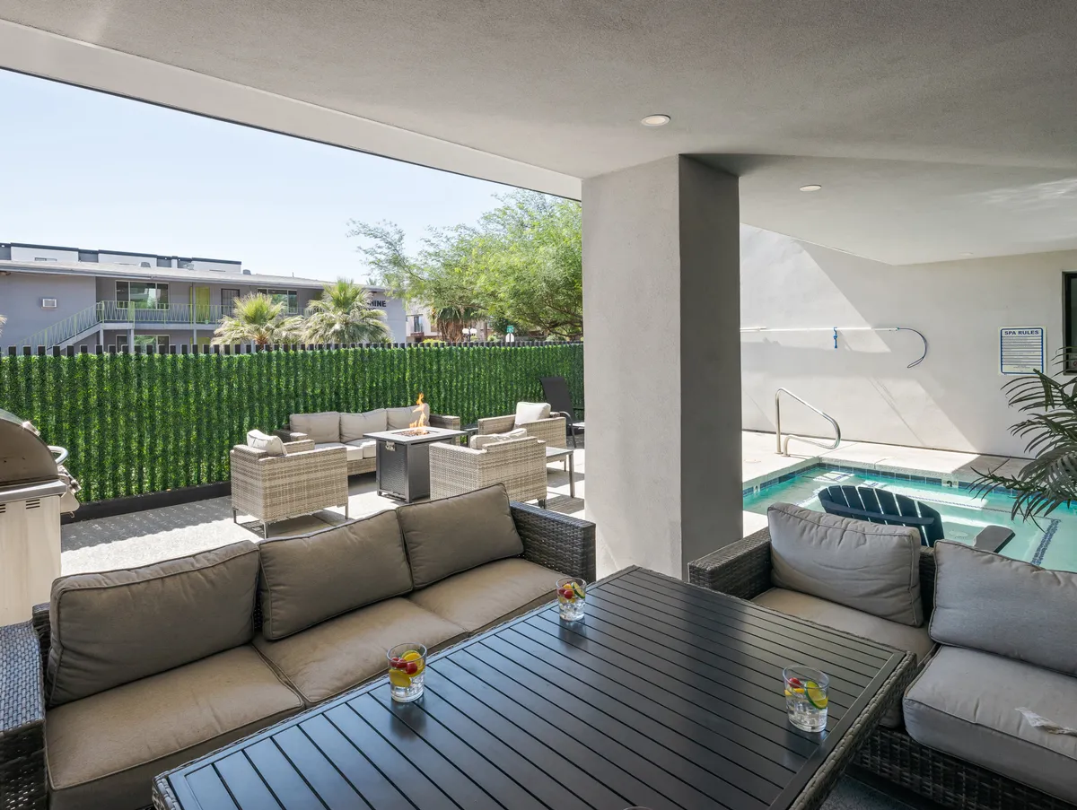 This image showcases an inviting outdoor seating area next to a swimming pool, surrounded by decorative greenery. The space suggests a relaxing environment perfect for socializing, unwinding after meetings, or hosting informal team gatherings.