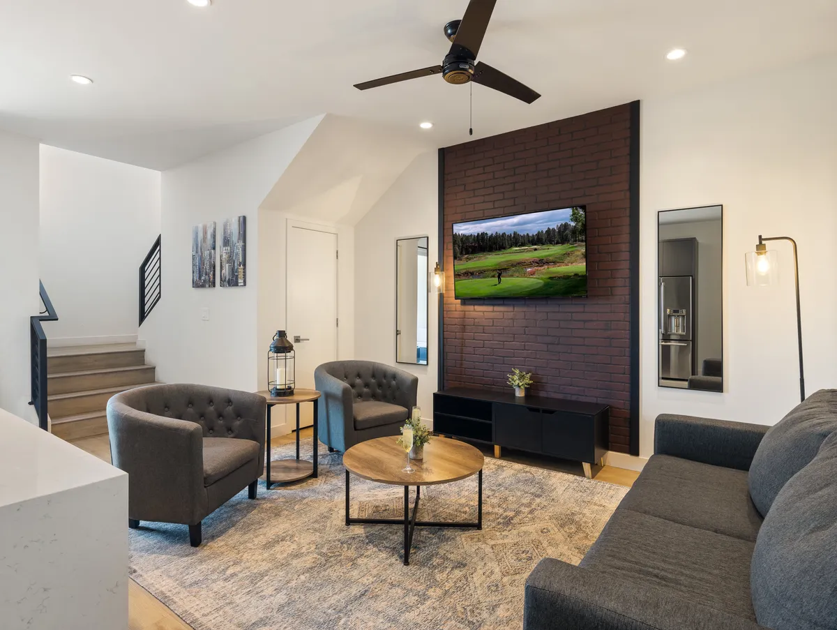 The hero image showcases a stylish, inviting living space featuring a plush sofa, sleek coffee table, large TV, and an accent brick wall, all illuminated by modern light fixtures. The setting is perfect for relaxing, socializing, or enjoying a cozy movie night with friends and family.